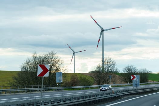 Dresden, Germany - April 24, 2023: Wind turbines stand along the highway along which the car moves.