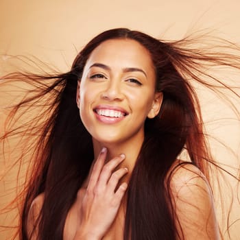 Hair care, beauty and portrait of happy woman with wind, luxury salon treatment and brown background. Smile, haircut and haircare, face of model with natural cosmetics and keratin shine in studio