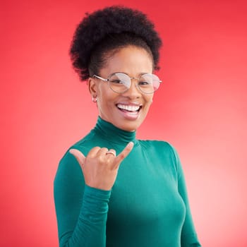Portrait, excited and black woman with call me hand in studio isolated on a red background with glasses. Face, happy and African person with shaka gesture, emoji sign and phone for communication.