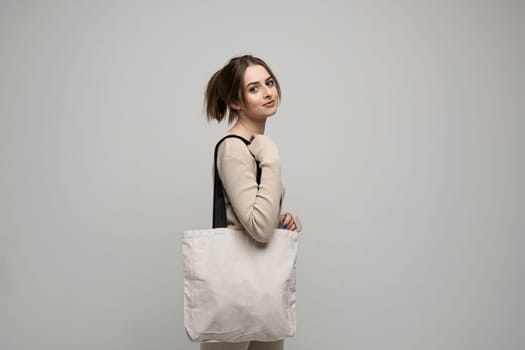 Brunette young girl holding linen shopping bag, mock up. Lady holding flax shopper handbag. Fashion and ecology concept