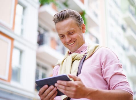 Happy man reading latest news articles from tablet PC while being outdoors on city street. Tablet PC in his hands allows him to access the latest information and stay up-to-date with current events. . High quality photo