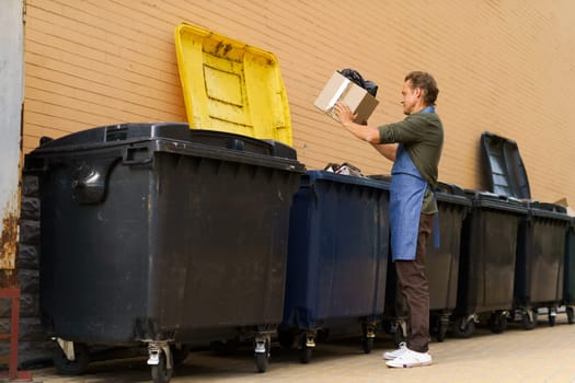 Diligent kitchen worker or waiter is seen responsibly disposing of garbage in city trash can. With sense of responsibility and cleanliness, he ensures proper waste management in urban environment. . High quality photo