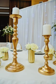 Gilded candlestick on a festive wedding table. Elegance wedding decor.