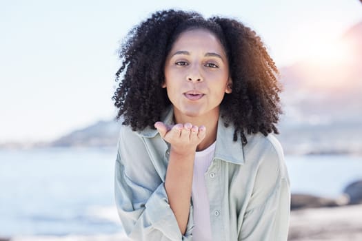 Woman at beach, portrait and blow kiss, love and freedom with travel, positive gesture and peace. Calm, happy and female person outdoor, young and carefree with emoji, care and romance with adventure.