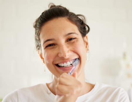 Healthcare, portrait of a woman brush her teeth and smile in her bathroom of her home. Hygiene or self care, health wellness or dental treatment and female person with brushing mouth with toothbrush.