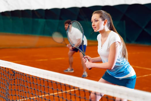 Pair of tennis players, man and woman waiting for service at indoor court