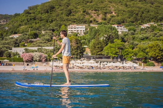 Young men Having Fun Stand Up Paddling in blue water sea near st stefan island in Montenegro. SUP.