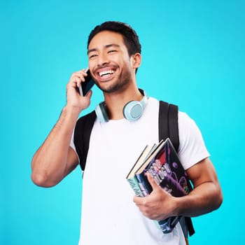 Talking, phone and college student in studio with backpack for university, education and studying books on blue background. Happy, man and person excited for learning and mobile network connection.