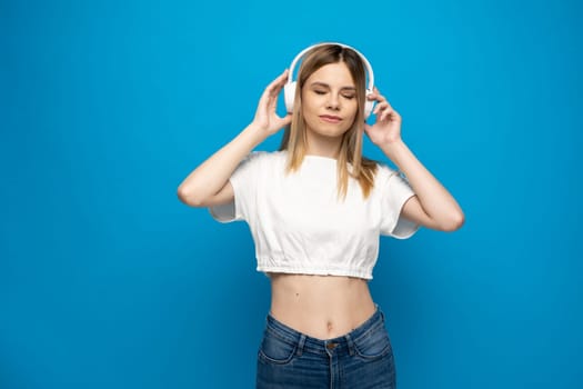Happy woman or teenage girl in white headphones listening to music from smartphone and dancing at home. People, leisure and technology concept
