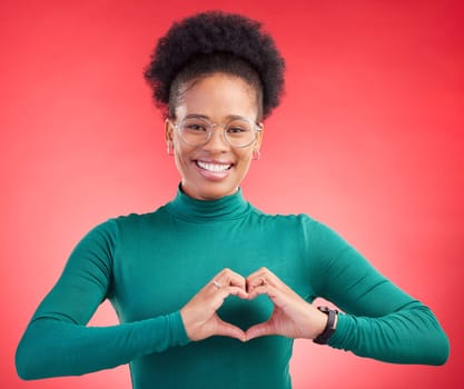 Happy woman, portrait and heart hands for love, care or romance against a red studio background. Female person smile with emoji, symbol or shape for romantic gesture, health support or like on mockup.