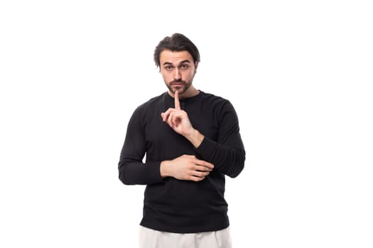 close-up of a young European brunette man with a stylish hairstyle and beard dressed in a black jacket among a white background with copy space.