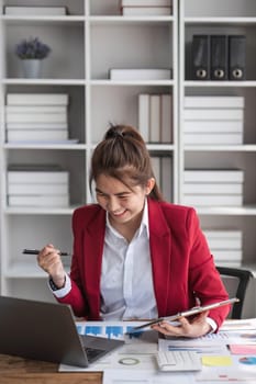 Beautiful Asian businesswoman celebrate while using laptop at office and showing delight. Startup small business and successful concept.