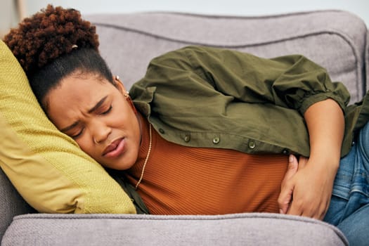 Sick woman, stomach pain and problem on sofa for ibs, health risk or nausea of gastric bloating, period cramps or virus. Black female person, menstruation or stress of constipation from endometriosis.