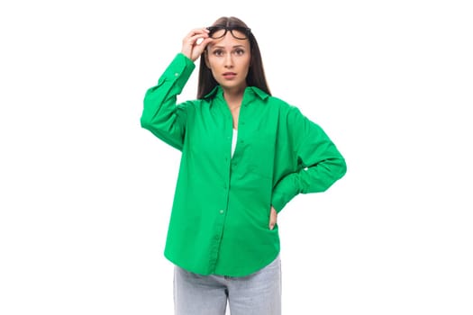 young european brown-eyed female model with well-groomed black hair and make-up dressed in a green shirt isolated on white background with copy space.
