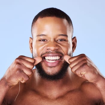 Portrait, black man and floss teeth in studio, healthy dental care or gum gingivitis. Face of male model cleaning mouth with oral thread for fresh breath, tooth cosmetics or plaque on blue background.