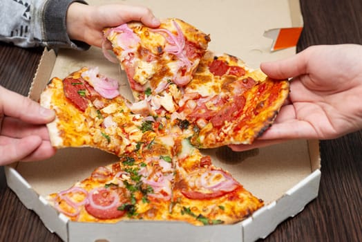 Close up of people hands taking slices of pizza. Group of friends or family sharing pizza together. Fast Food, Leisure, Lifestyle.
