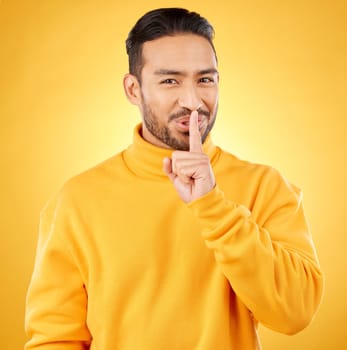 Secret, man and finger on lips for gossip, confidential information or sign with hand for whisper in studio or yellow background. Announcement, emoji or person for communication or silence of sound.