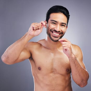 Flossing teeth, studio portrait or happy man with oral health hygiene, wellness grooming or tooth treatment string. Morning bathroom routine, aesthetic smile or dental care person on gray background.