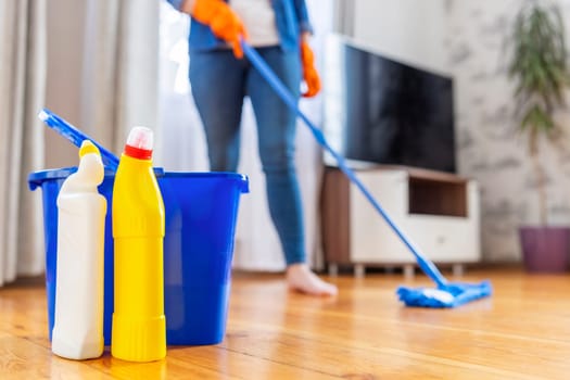 A young woman washes the floor with a mop in the living room. Cleaning service. Housework and housekeeping concept