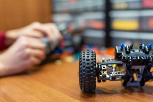 Kid playing with developing mechanics constructor kit, creates different mechanisms