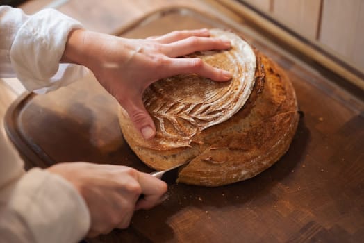 Baking bread at home, cutting fresh aromatic loan of bread