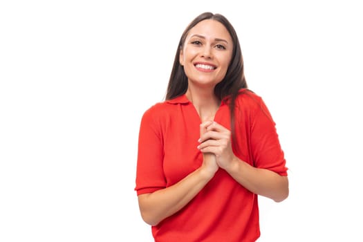 young smiling european woman with dark straight hair dressed in a red short sleeve shirt on a white background with copy space.