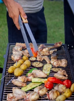 a man is grilling vegetables and meat. Selective focus. Nature