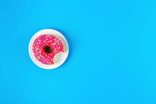 donut on a blue background. glazed donut with sprinkles lies with copy space. Long horizontal banner. top view or flat lay.