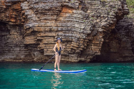 Young women Having Fun Stand Up Paddling in blue water seaamong the rocks in Montenegro. SUP.
