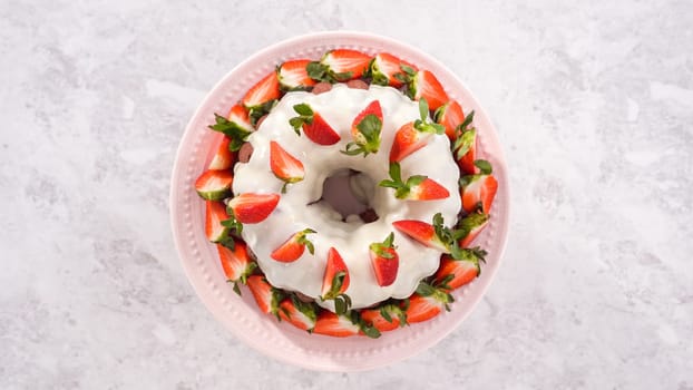 Flat lay. Step by step. Decorating freshly baked red velvet bundt cake with organic strawberries.