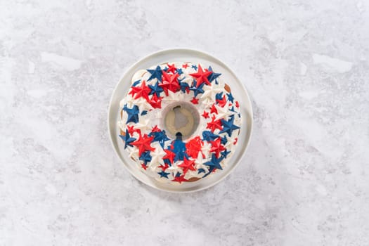 Flat lay. July 4th bundt cake covered with a vanilla glaze and decorated with chocolate stars on a white plate.