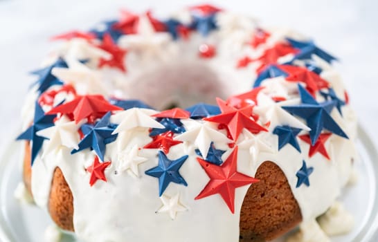 July 4th bundt cake covered with a vanilla glaze and decorated with chocolate stars on a white plate.