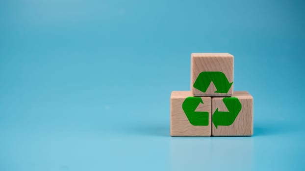 Stacked wooden blocks with green recycle symbol. Recycling concept.