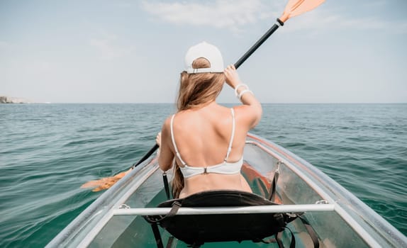 Woman in kayak back view. Happy young woman with long hair floating in transparent kayak on the crystal clear sea. Summer holiday vacation and cheerful female people having fun on the boat.