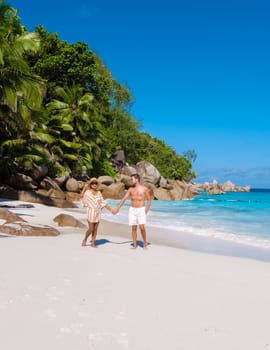 Anse Lazio Praslin Seychelles, a young couple of men and women on a tropical beach during a luxury vacation in Seychelles. Tropical beach Anse Lazio Praslin Seychelles Islands on a sunny day