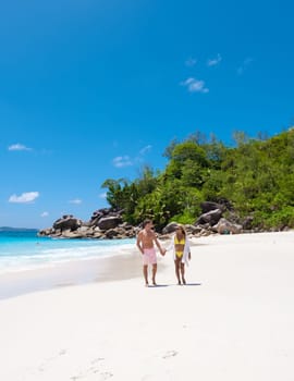 Anse Lazio Praslin Seychelles is a young couple of men and women on a tropical beach during a luxury vacation there. Tropical beach Anse Lazio Praslin Seychelles tropical Islands