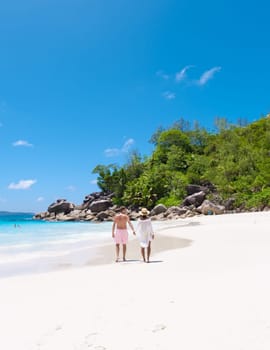 Anse Lazio Praslin Seychelles a young couple of men and women on a tropical beach during a luxury vacation there. Tropical beach Anse Lazio Praslin Seychelles Islands on a sunny day with a blue sky