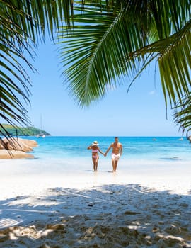 Anse Lazio Praslin Seychelles is a young couple of men and women on a tropical beach during a luxury vacation there. Tropical beach Anse Lazio Praslin Seychelles Islands