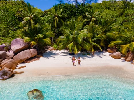 Anse Lazio Praslin Seychelles, a young couple of men and women on a tropical beach during a luxury vacation at the Seychelles. Tropical beach Anse Lazio Praslin Seychelles Islands drone aerial view