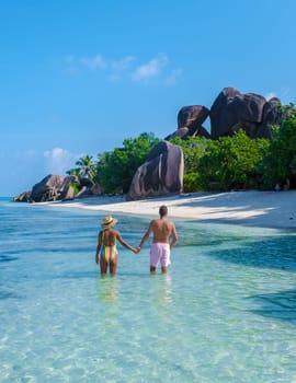 a young couple of men and women on a tropical beach during a luxury vacation in Seychelles. Tropical beach Anse Source d'Argent, La Digue Seychelles