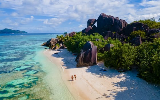 Anse Source d'Argent, La Digue Seychelles, a young couple of men and women on a tropical beach during sunset, drone aerial view