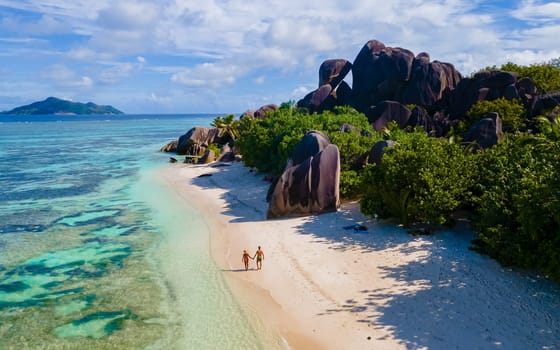 Anse Source d'Argent, La Digue Seychelles, a young couple of men and women on a tropical beach during a luxury vacation in Seychelles. drone view from above at a tropical beach