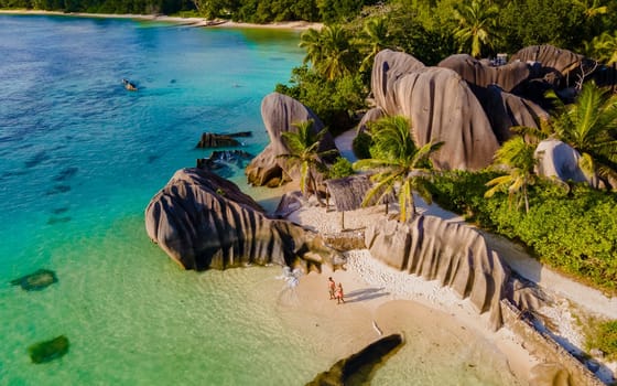 Anse Source d'Argent, La Digue Seychelles, a young couple of men and women on a tropical beach during a luxury vacation in Seychelles. drone view from above at a tropical beach