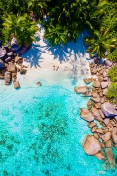 Anse Lazio Praslin Seychelles is a young couple of men and women on a tropical beach during a luxury vacation there. Tropical beach Anse Lazio Praslin Seychelles Islands on a sunny day