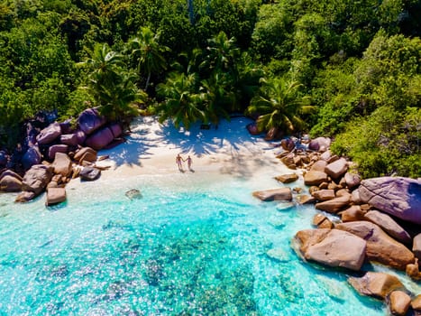 Anse Lazio Praslin Seychelles is a young couple of men and women on a tropical beach during a luxury vacation there. Tropical beach Anse Lazio Praslin Seychelles Islands on a sunny day