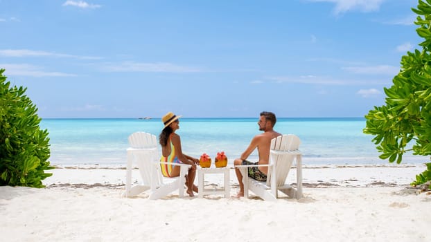 A couple of men and women are on the beach with a coconut drink at Praslin Island Seychelles. a tropical island with a white beach and blue ocean, the beach of Anse Volbert Seychelles.