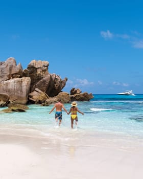 Anse Cocos La Digue Seychelles, a young couple of men and women on a tropical beach during a luxury vacation in Seychelles. Tropical beach Anse Cocos La Digue Seychelles with a blue ocean