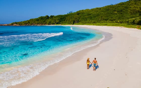 Anse Cocos La Digue Seychelles, a young couple of men and women on a tropical beach during a luxury vacation in Seychelles. Tropical beach Anse Cocos La Digue Seychelles with a blue ocean