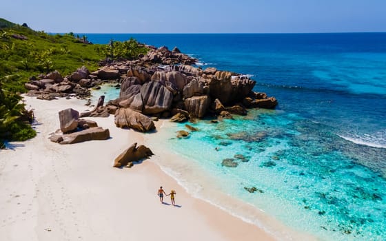 men and woman at the beach of Anse Cocos La Digue Seychelles, a young couple on a tropical beach during a luxury vacation in Seychelles. Tropical beach Anse Cocos La Digue Seychelles.