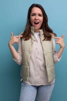 surprised brunette young lady in casual outfit on studio background.